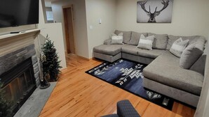 A modern living room with a sectional sofa, a fireplace, and a mounted TV. - Cozy Mountain Condo (Windham)