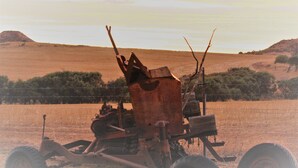 Un vehículo militar grande y oxidado con un arma montada en un paisaje desolado.