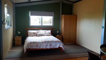 A bedroom with a bed, bedside tables, a wardrobe, a window, and a small table with chairs.