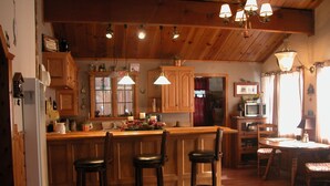 A cozy kitchen with wooden cabinets, a bar area, and a dining space with a table and chairs.