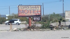 Een motelbord met de naam 'Copper Sands Motel' en een telefoonnummer.