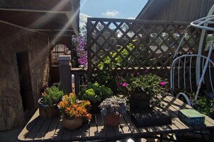 Una terraza de madera con plantas en macetas y una silla de metal.