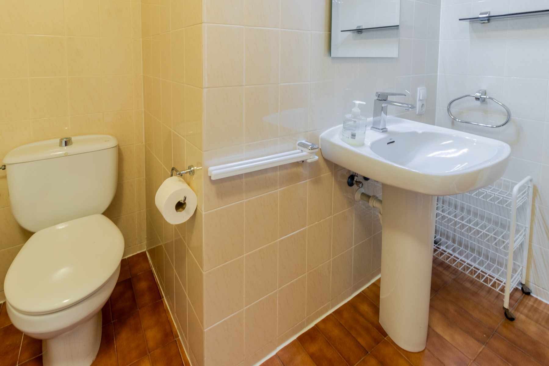 Un baño con dos inodoros, un lavabo y un secador de manos.