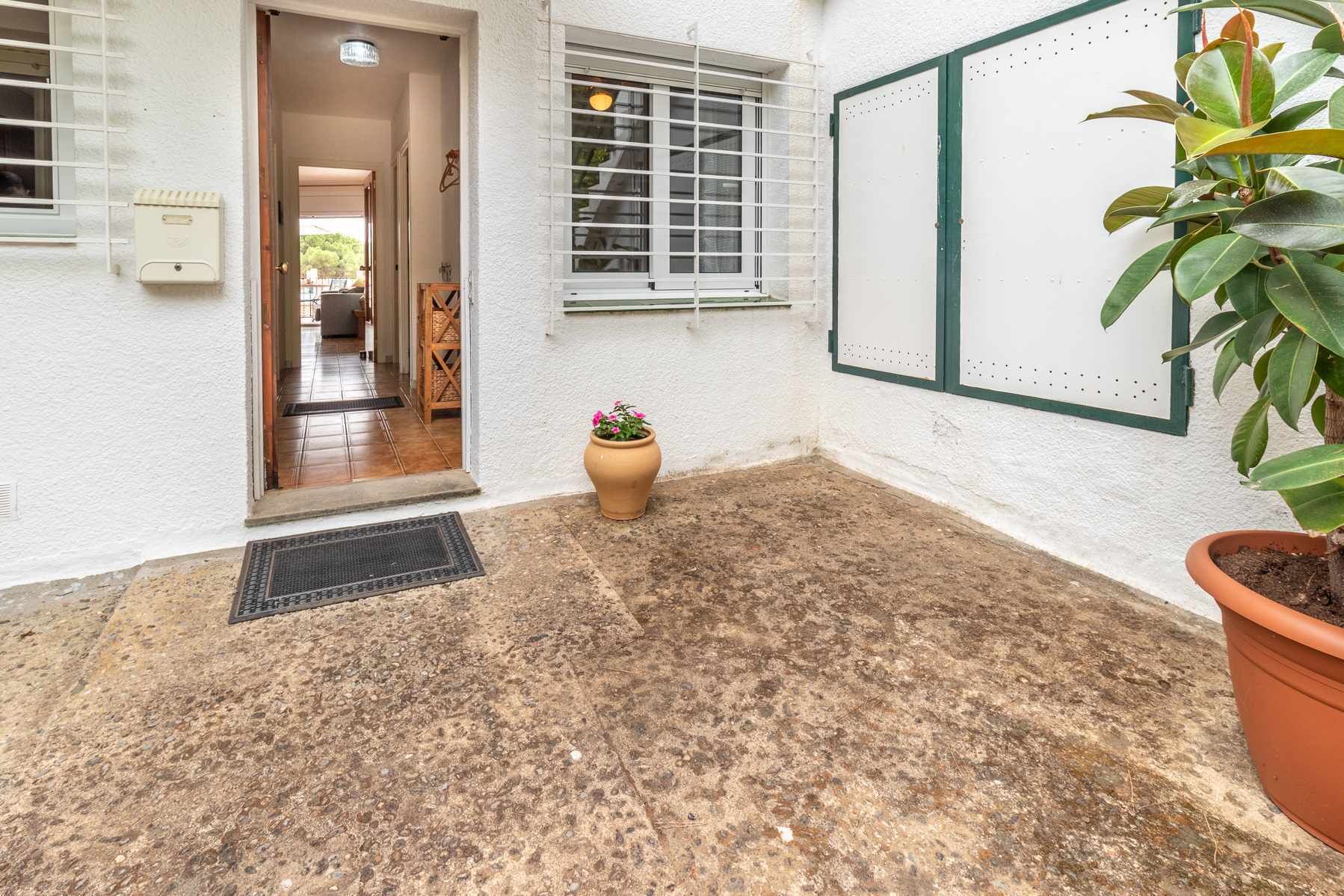 A courtyard with a tiled floor, a potted plant, and a door leading to an interior space.