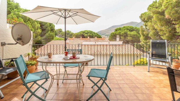 Un patio con una mesa redonda, dos sillas, una antena parabólica y una parrilla.