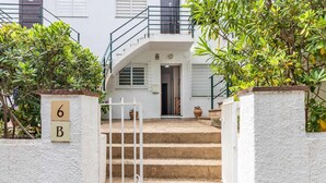Un edificio blanco con una escalera que lleva a una puerta, rodeado de vegetación.