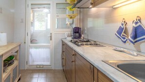 Una cocina compacta con estufa a gas, un lavamanos y armarios de madera.
