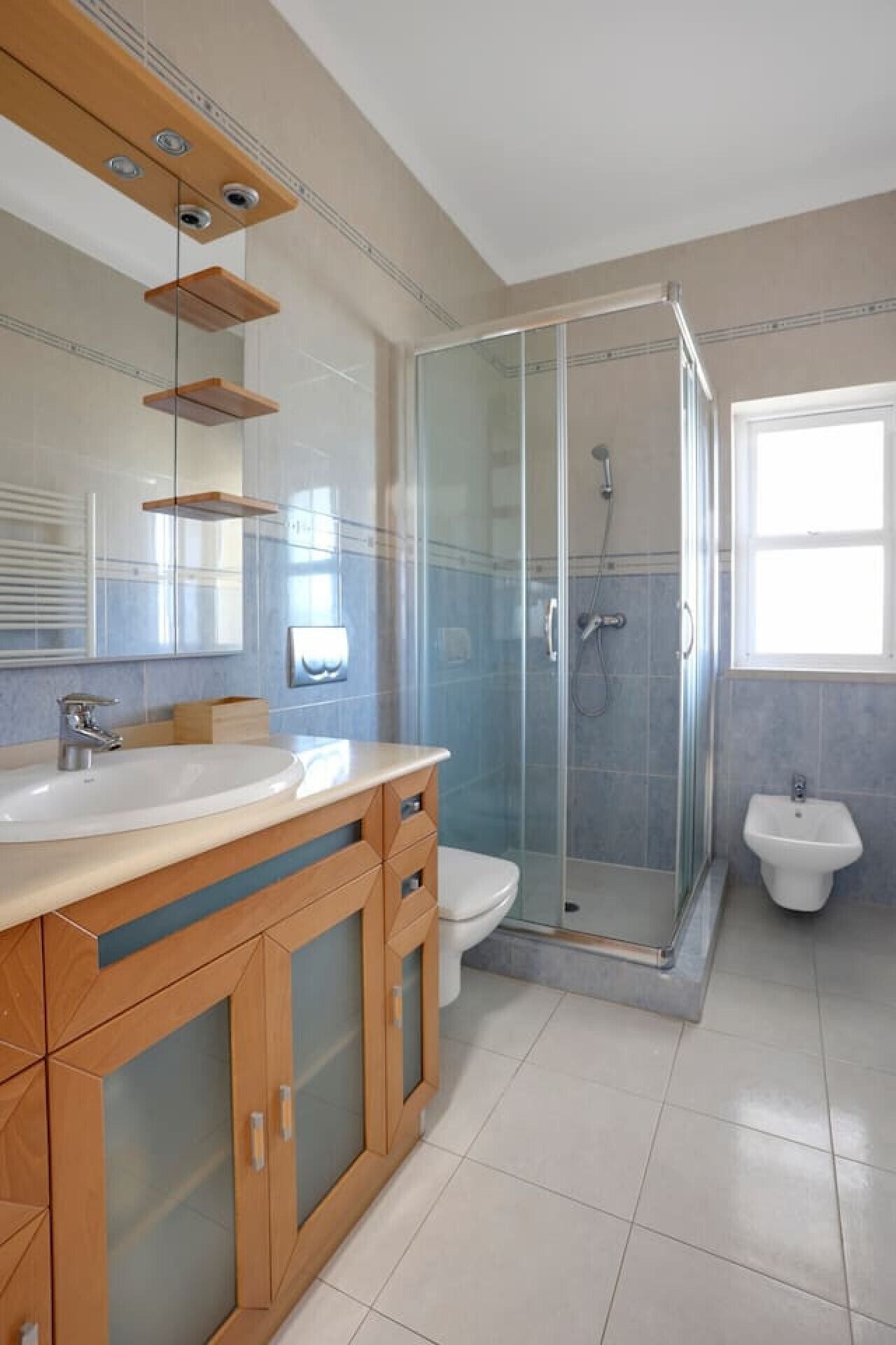 Ein modernes Badezimmer mit Glasdusche, separater Toilette und Waschtisch mit Spüle und Spiegel.