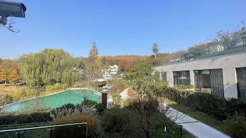 A modern building with large windows and a swimming pool surrounded by trees.