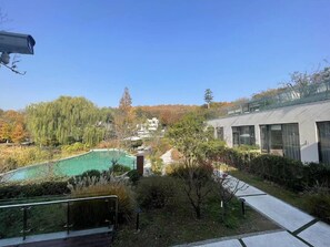A modern building with large windows and a swimming pool surrounded by trees. - Blossom Hill Hotel Nanjing Bojin (Nanjing)