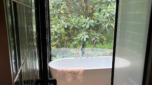 A modern bathroom with a freestanding bathtub, a glass shower enclosure, and a view of lush greenery outside. - Blossom Hill Hotel Nanjing Bojin (Nanjing)