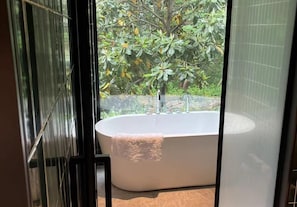 A modern bathroom with a freestanding bathtub, a glass shower enclosure, and a view of lush greenery outside. - Blossom Hill Hotel Nanjing Bojin (Nanjing)
