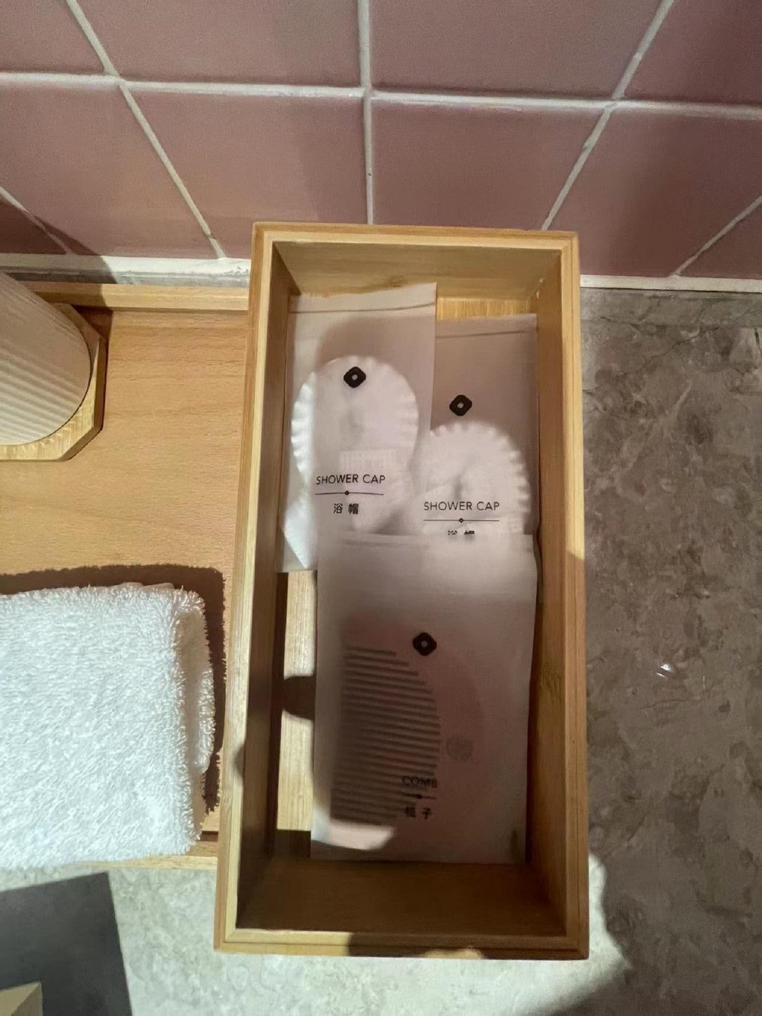 Une boîte en bois contenant deux bonnets de douche blancs, chacun étant muni d’une étiquette.