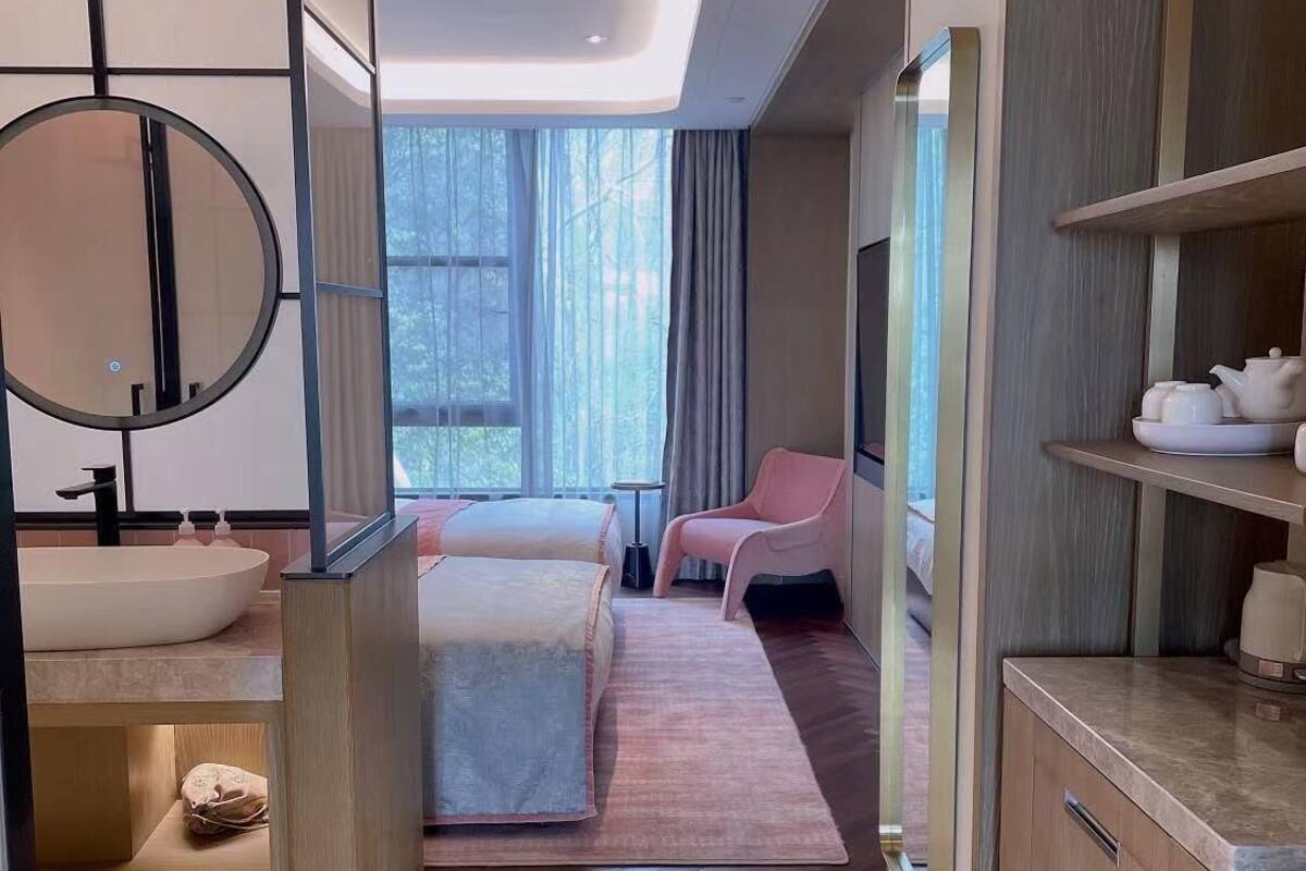 Ein modernes Hotelzimmer mit Bad, einem Bett, einer Sitzecke und einer Küchenzeile.
