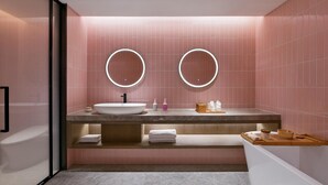 A modern bathroom with a large sink, two round mirrors, and pink tiled walls. - Blossom Hill Hotel Nanjing Bojin (Nanjing)