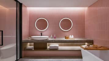 Un baño moderno con un lavamanos grande, dos espejos redondos y paredes con azulejos rosas.