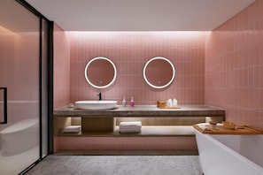 A modern bathroom with a large sink, two round mirrors, and pink tiled walls. - Blossom Hill Hotel Nanjing Bojin (Nanjing)