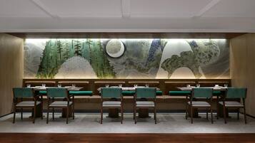 Un restaurante con una barra larga, cabinas tapizadas de verde y un mural grande en la pared.