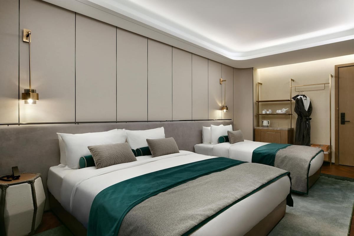 Ein Hotelzimmer mit zwei Betten, einem Nachttisch, einem Kleiderschrank und einem Spiegel.