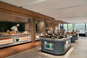 A modern kitchen with a chef preparing food, large windows, and a clean, organized layout. - Blossom Hill Hotel Nanjing Bojin (Nanjing)