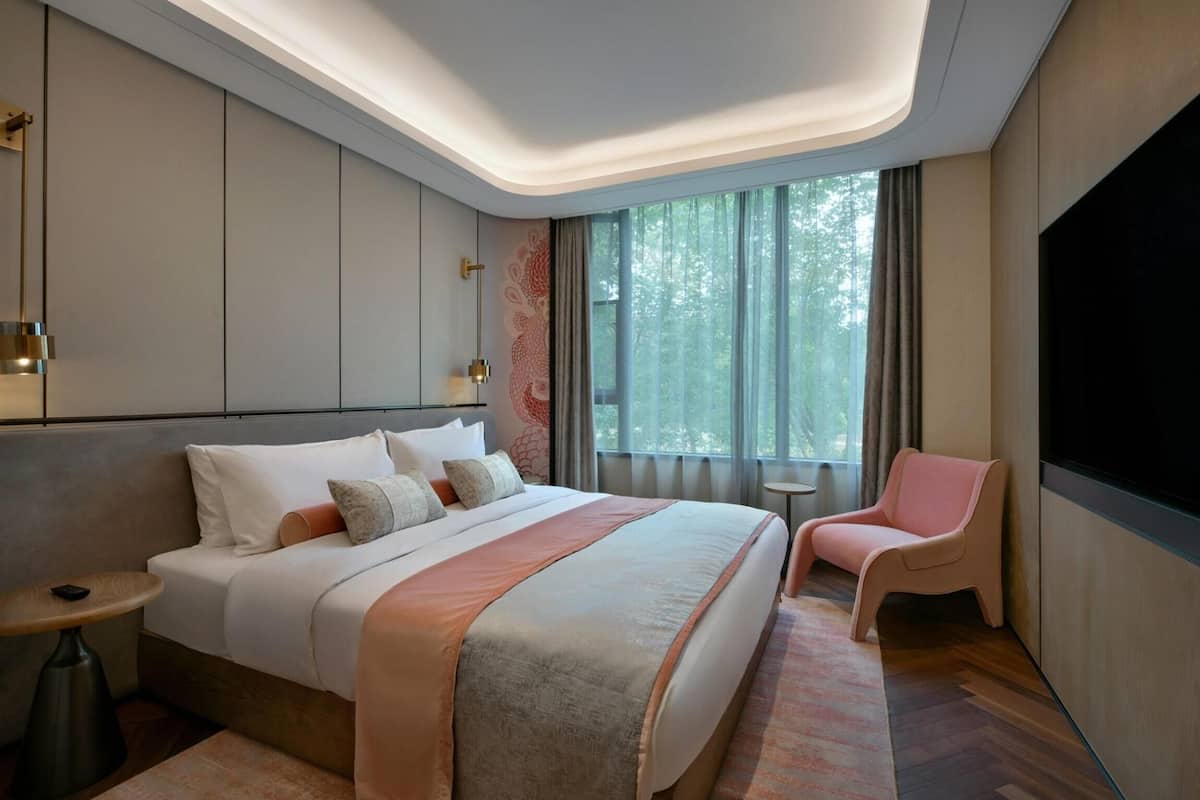 Ein modernes Hotelzimmer mit einem großen Bett, einer kleinen Sitzecke und einem Fernseher.