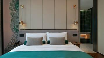 A modern hotel room with a large bed, a peacock mural, and a view of a tiled wall.