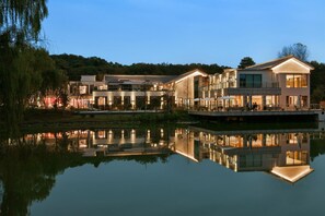 A modern hotel with a reflective pool, multiple buildings, and a forested hill in the background. - Blossom Hill Hotel Nanjing Bojin (Nanjing)