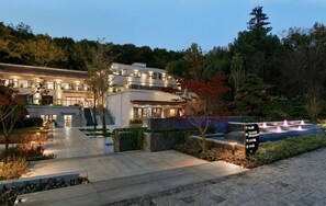 A modern multi-story hotel with a well-lit entrance, landscaped gardens, and a fountain. - Blossom Hill Hotel Nanjing Bojin (Nanjing)