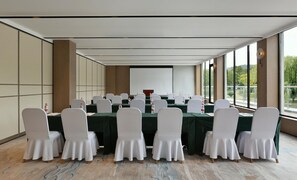 A conference room with a long table, white chairs, and a projector screen. - Blossom Hill Hotel Nanjing Bojin (Nanjing)