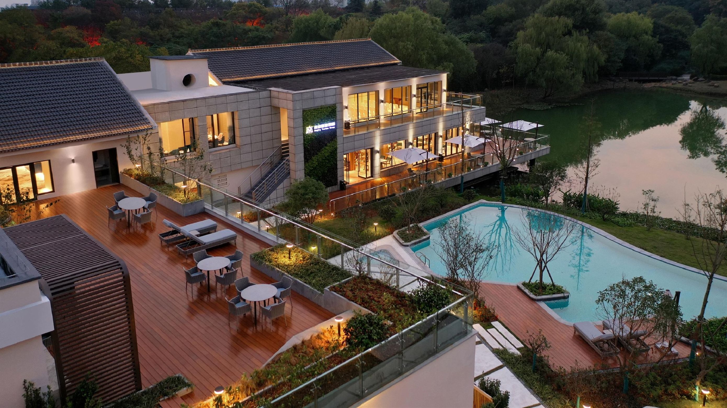 Un hotel moderno con piscina en la azotea, mobiliario exterior y vistas a un lago.