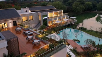 A modern hotel with a rooftop pool, outdoor seating, and a view of a lake.