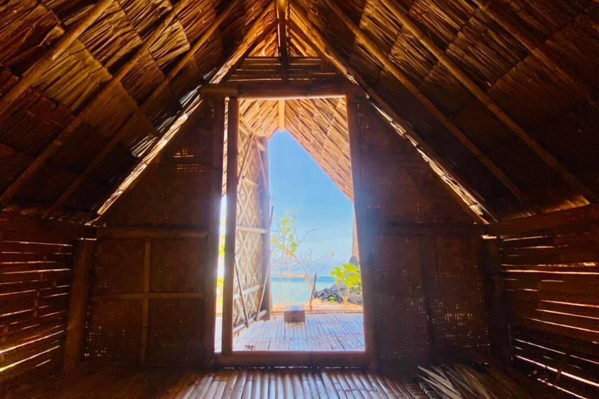 An interior view of a wooden structure with a sloped roof and a doorway leading outside.