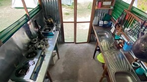 Una cocina compacta con estufa a gas, lavamanos y varios utensilios.