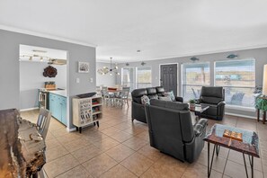A modern living room with a sofa, a coffee table, and a dining area with a table and chairs.
