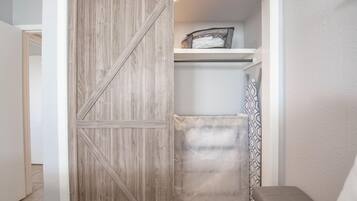 A walk-in closet with a sliding barn-style door, a shelf with folded clothes, and a patterned curtain.