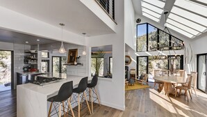 A spacious kitchen with a central island, modern pendant lighting, and a dining area with a large wooden table and chairs. - Riverfront Retreat w/ Mountain Views (Buena Vista)