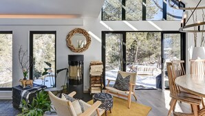 A modern living room with a fireplace, large windows, and a dining area. - Riverfront Retreat w/ Mountain Views (Buena Vista)