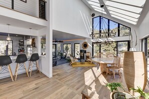 Un interior espacioso con techo alto, ventanas amplias y una zona de comedor con luz natural.