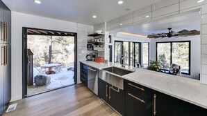A modern kitchen with a large island, built-in appliances, and large windows offering views of the outdoors. - Riverfront Retreat w/ Mountain Views (Buena Vista)