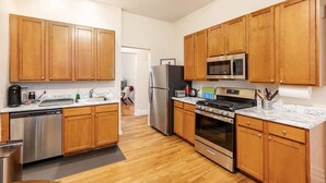 A modern kitchen with wooden cabinets, stainless steel appliances, and a marble countertop. - Cozy two bedroom close to Wrigley Field (Chicago)