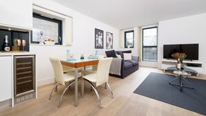 A modern living space with a dining area, a sofa, a TV, and a balcony.