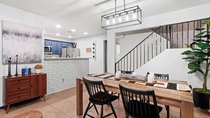 Una cucina moderna con mobili bianchi, un tavolo da pranzo in legno e sedie nere.
