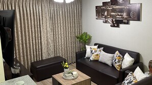 A modern living room with a dark brown sofa, a coffee table, and a dining area with a table set for two. - “Sea View Apartment: Near Airport. Air,C. Free Parking.” (San Miguel)