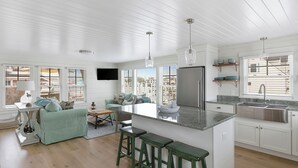 Una cocina moderna con una isla central, taburetes de bar y un amplio ventanal.