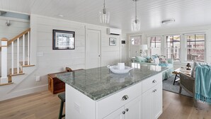 Una cocina amplia con una isla grande, armarios blancos e iluminación colgante.