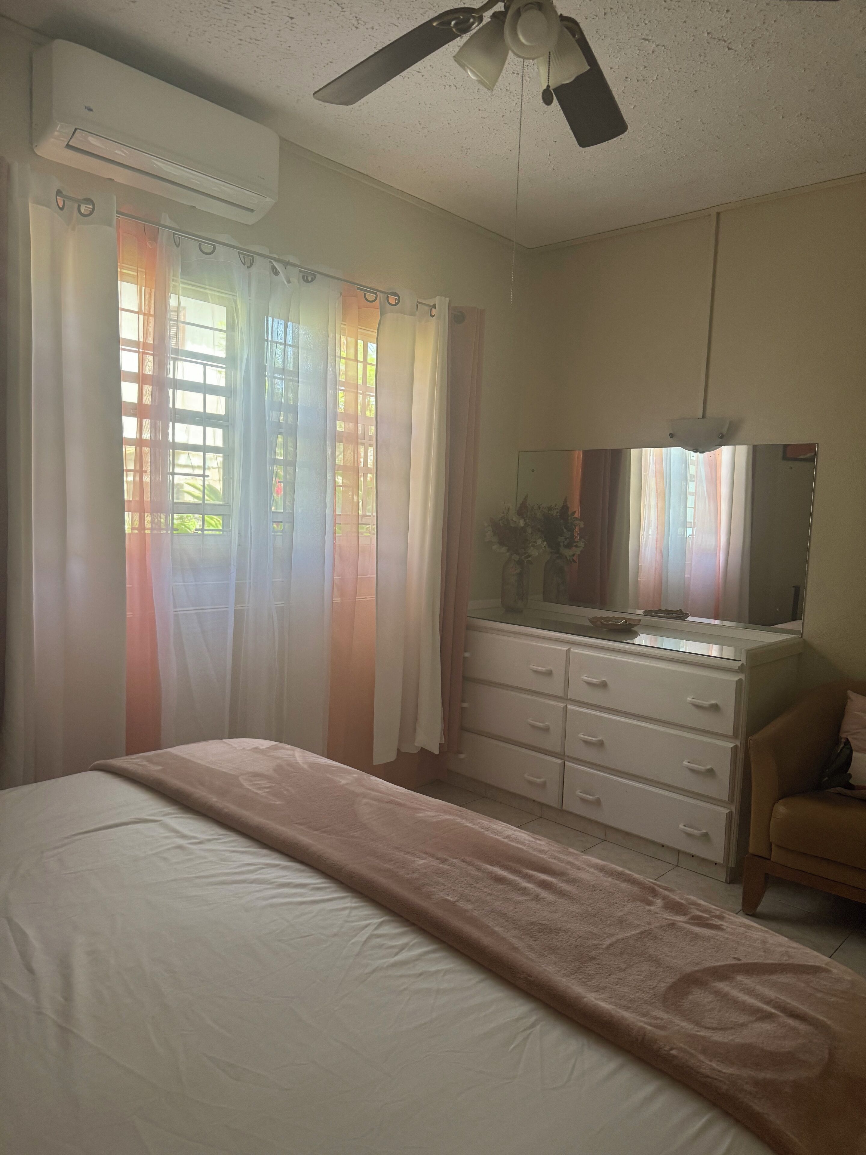 Quarto com cama, penteadeira, espelho e ventilador de teto.