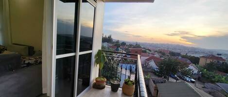 A balcony with large sliding glass doors, a sofa, and potted plants.