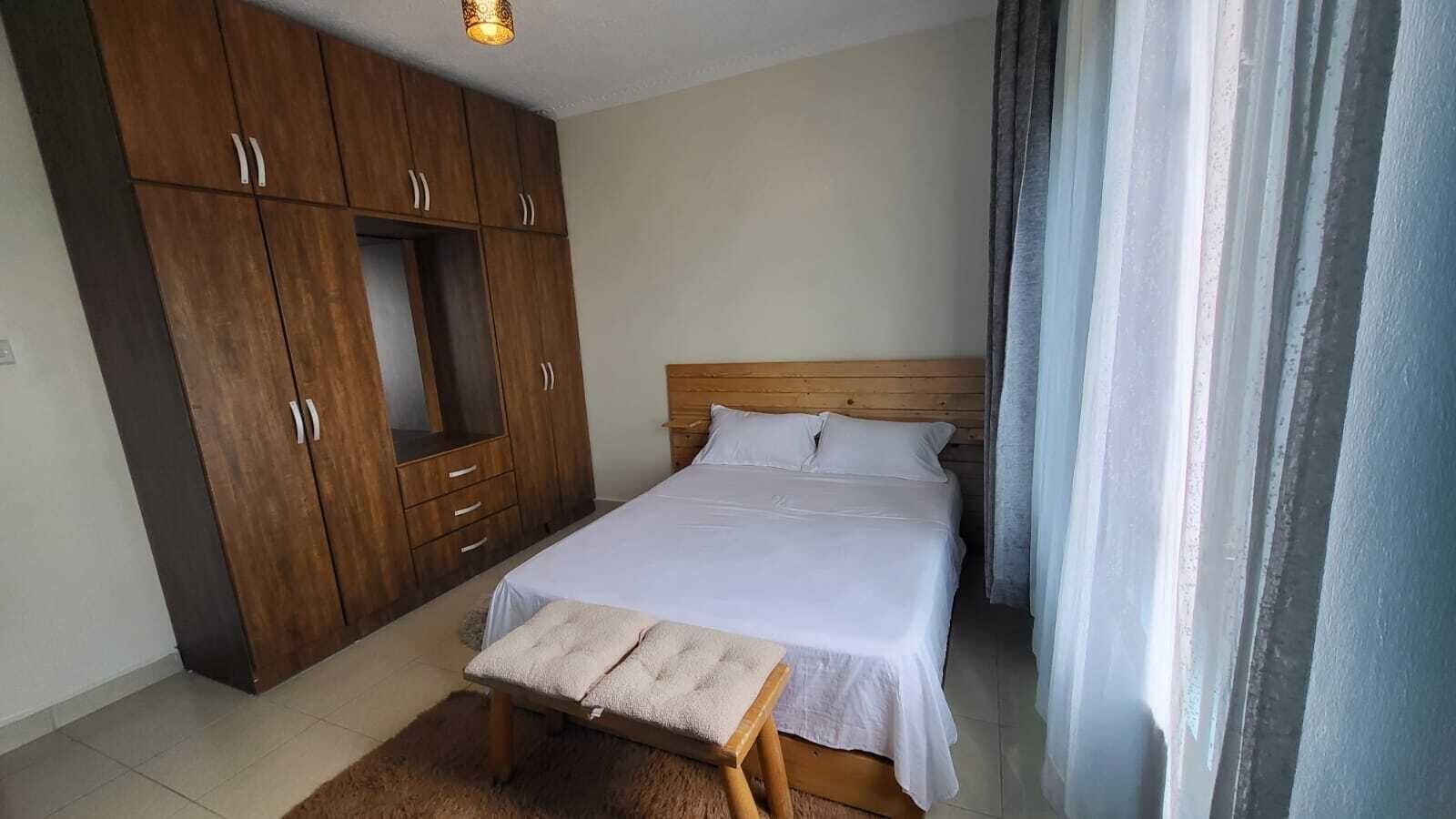 Ein Schlafzimmer mit Bett, Holzschrank und Sitzbank.