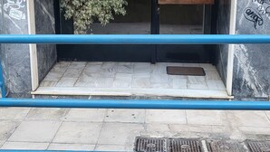 Une entrée d’immeuble avec une plaque portant le numéro 89, un portail en métal et un petit banc.