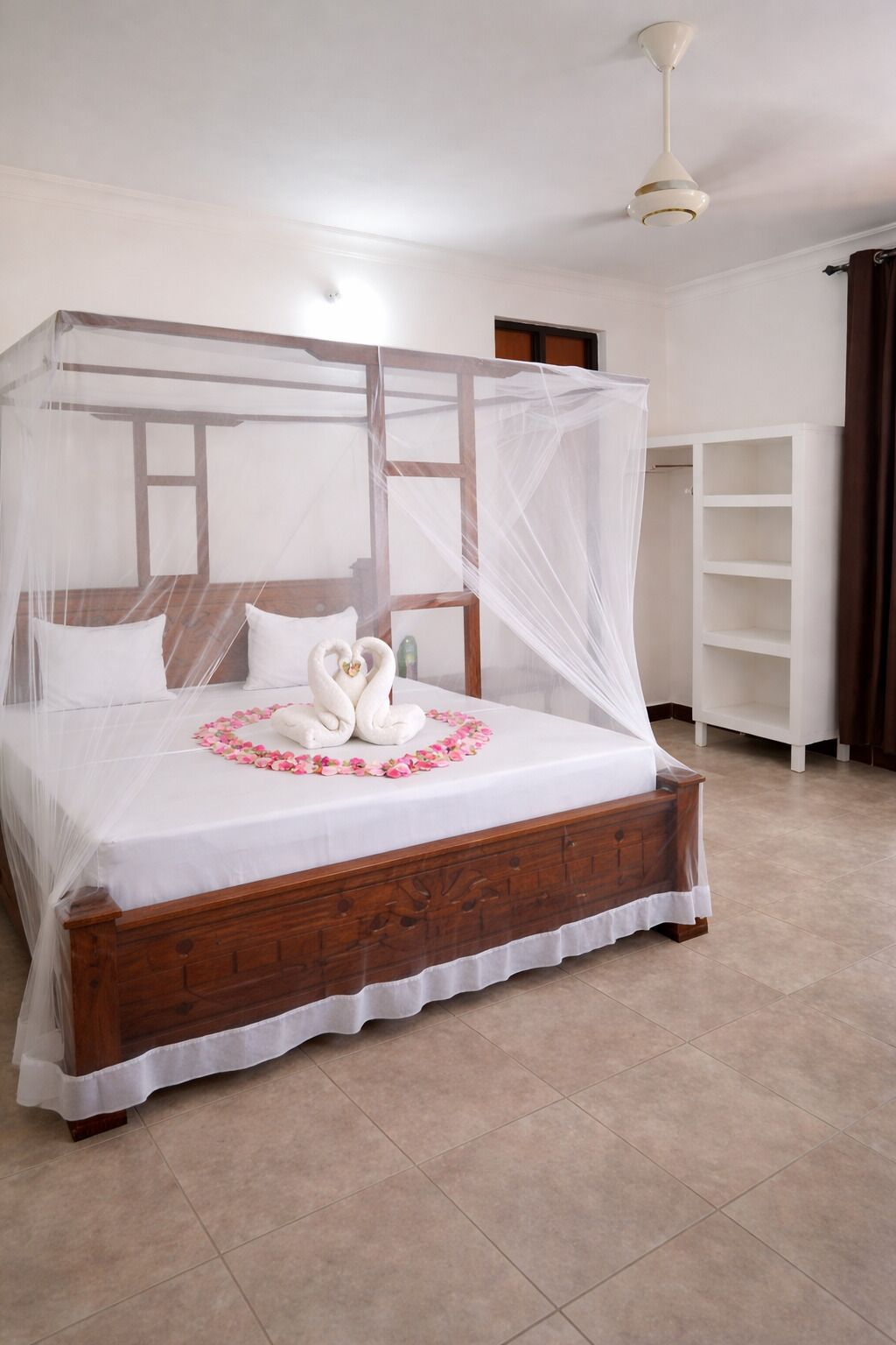 Un dormitorio con cama con dosel, dosel blanco y cabecera de madera.